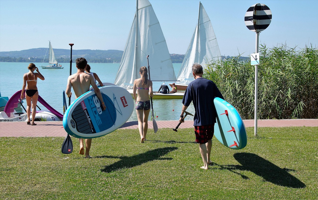 People with stand-up paddleboards by Lake Balaton